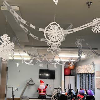 A festive gym space adorned with stylish holiday decorations, including paper snowflakes and a Santa figure.