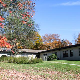A serene view of a building surrounded by vibrant autumn foliage and a clear blue sky.