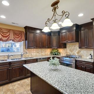 A modern kitchen with dark wood cabinets and a granite island.