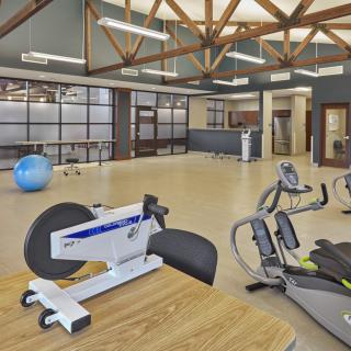 A spacious gym with various exercise equipment and a modern design.