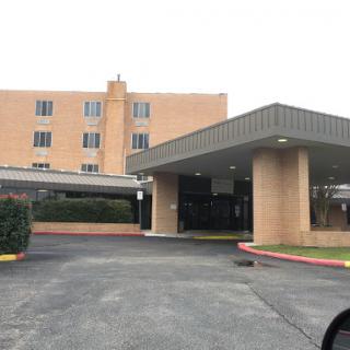 A view of a hotel entrance with a parking area.