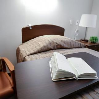 A cozy bedroom setup with an open book on a table beside the bed.