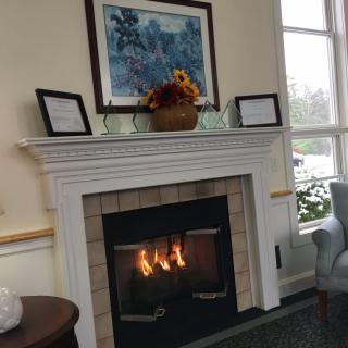 A cozy living room featuring a fireplace adorned with artwork and floral decor.
