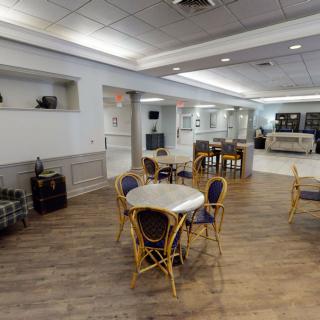 A spacious and modern cafe interior with tables and chairs, featuring a wooden floor and bright lighting.