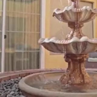 A decorative outdoor stone fountain with water gently cascading from tier to tier.