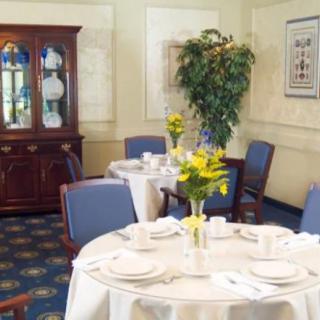 An elegant dining room with neatly set tables, upholstered chairs, and a decorative china cabinet.