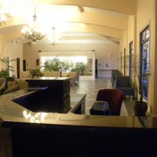 A modern hotel lobby with a reception desk and seating area.