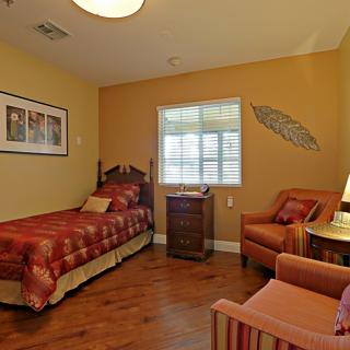A cozy bedroom with a single bed, armchair, and wall decor.