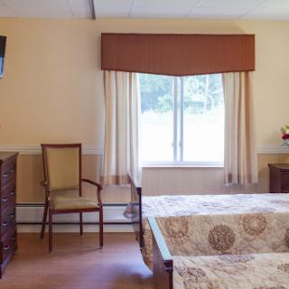 A cozy hotel room featuring a bed, a chair, a TV, and a view through the window.