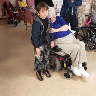 A young child sharing a tender moment with an elderly woman in a care facility.