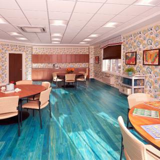 A cozy dining area with round tables, comfortable chairs, and vibrant wooden flooring.