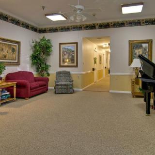 A cozy living room with comfortable seating, framed artwork, and a piano.