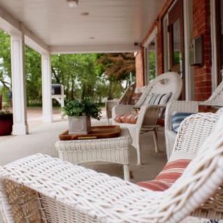 A cozy porch with wicker furniture and potted plants, perfect for relaxation.