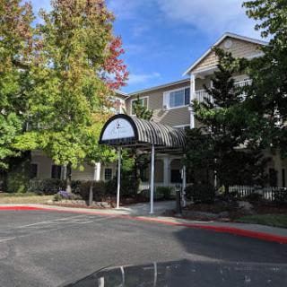 A building entrance with an awning surrounded by trees on a sunny day.