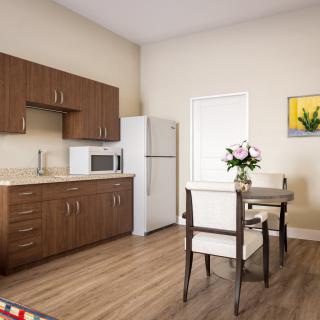 A cozy kitchen and dining area with wooden cabinets, a refrigerator, and a small dining table set.