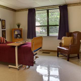 A neatly arranged hospital room with a bed and a chair by the window.