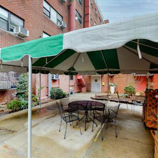 A cozy outdoor patio area with a green and white striped tent, seating arrangements, and a relaxing ambiance.