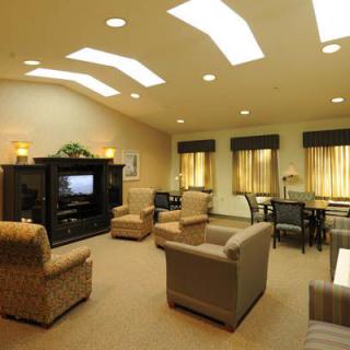 A cozy living room with comfortable seating and a television, illuminated by skylights.