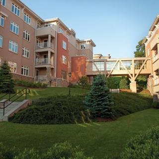 A residential complex with a connecting bridge and landscaped greenery.