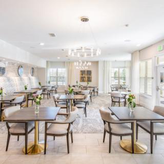 A modern and elegant dining area with neatly arranged tables, chairs, and floral decorations.
