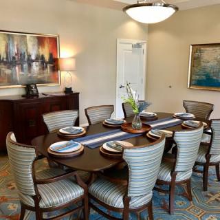 A well-furnished dining room with a set table, elegant chairs, and artwork on the walls.
