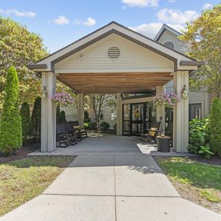 A building entrance with a canopy surrounded by trees and landscaping.