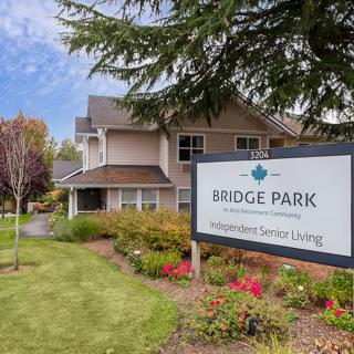 A senior living facility with a well-maintained garden and clear signage under a cloudy sky.
