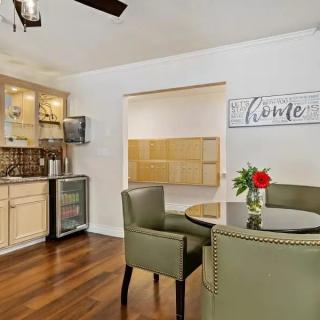 A modern kitchen and dining area featuring a hardwood floor, round table with green chairs, and a bar cabinet.