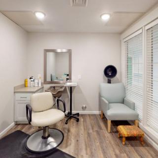 A modern hair salon interior featuring a styling chair, mirror, and waiting area.