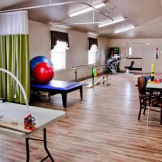 A spacious therapy room equipped with exercise equipment for rehabilitation and physical therapy sessions.