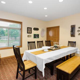A dining room with a wooden table, chairs, and a bench, complemented by decor on the walls.
