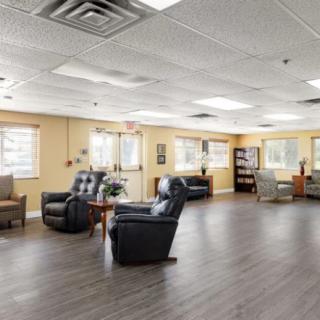 A spacious waiting room with comfortable lounge chairs and a wooden floor, brightly lit by multiple windows.