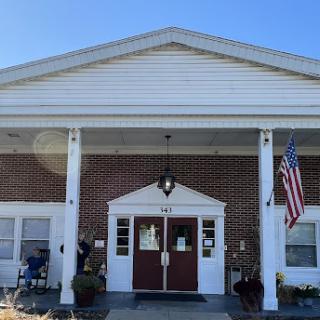 A welcoming entrance to a building, featuring classic architecture and an American flag.