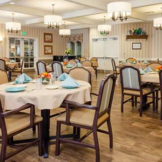 An elegantly set dining room with neatly arranged tables and chairs, accentuated by chandeliers and tasteful decor.