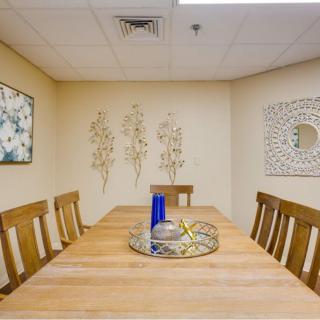 A cozy dining room with a wooden table and chairs, adorned with wall art and a decorative vase centerpiece.