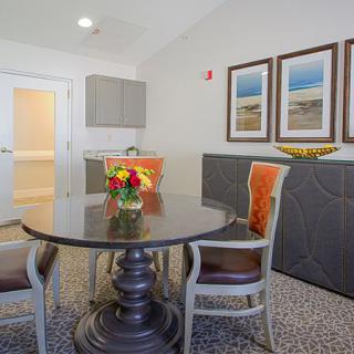 A modern dining area featuring a dark wooden table with chairs, decorated with vibrant flowers and framed artwork on the walls.