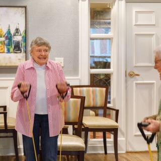 Elderly individuals participating in a group exercise session using resistance bands indoors.