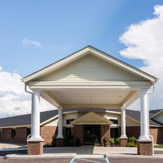 A welcoming entrance of a hospitality building, featuring elegant columns under a clear blue sky.