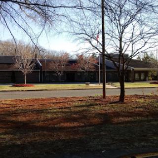 A serene view of a modern building surrounded by trees and open grass.