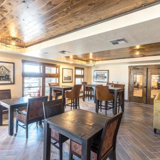 A cozy dining area featuring wooden tables and chairs with warm lighting.
