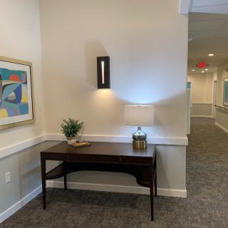 A well-decorated hallway featuring a table with a lamp, artwork on the wall, and a small plant for decoration.