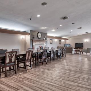 A spacious dining room with long wooden tables and chairs, featuring a fireplace and wood flooring.