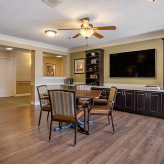 A cozy living space featuring a dining area with four chairs, a large television mounted on the wall, and elegant wood flooring.