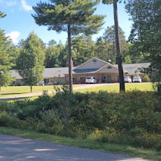 A scenic view featuring a building surrounded by trees and lush greenery, with a road in the foreground.