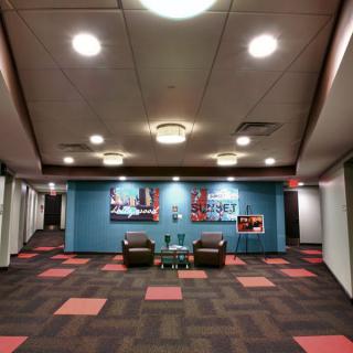 A modern lobby with colorful carpet tiles, artwork on the walls, and seating arrangements.