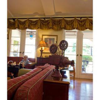 A cozy living room with vintage decor and elegant drapes framing the windows.