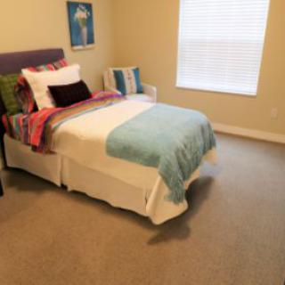 A cozy bedroom with a neatly made bed and soft carpet.