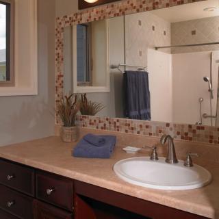 A clean and organized bathroom with a mirror above the sink, neatly folded towels, and decorative elements on the countertop.