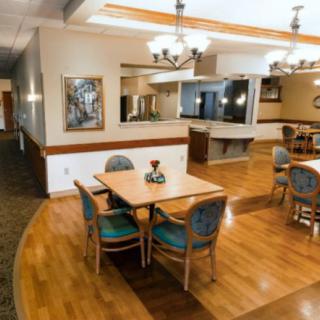 A cozy dining area with wooden floors, tables, and chairs, adorned with chandeliers and decorative elements.