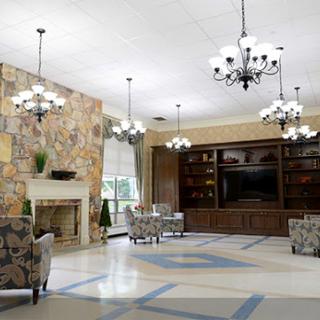 A spacious and elegantly designed lobby featuring comfortable seating, stylish chandeliers, and a beautiful stone wall.